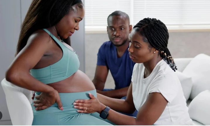 Black African mother holding newborn baby in a warm maternity setting at Omega Clinic